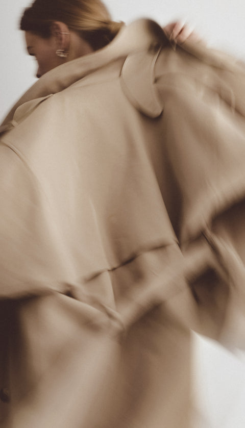 Close-up of a woman wearing a beige coat with a blurred background