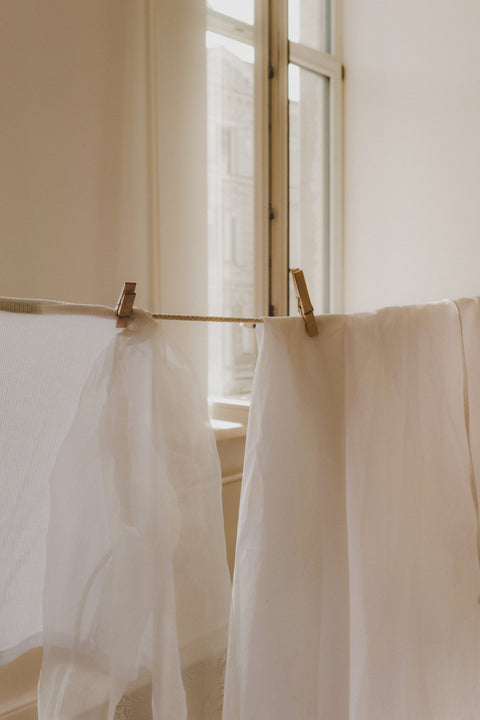 Sheer white fabrics hanging from a rod with a blurred indoor background