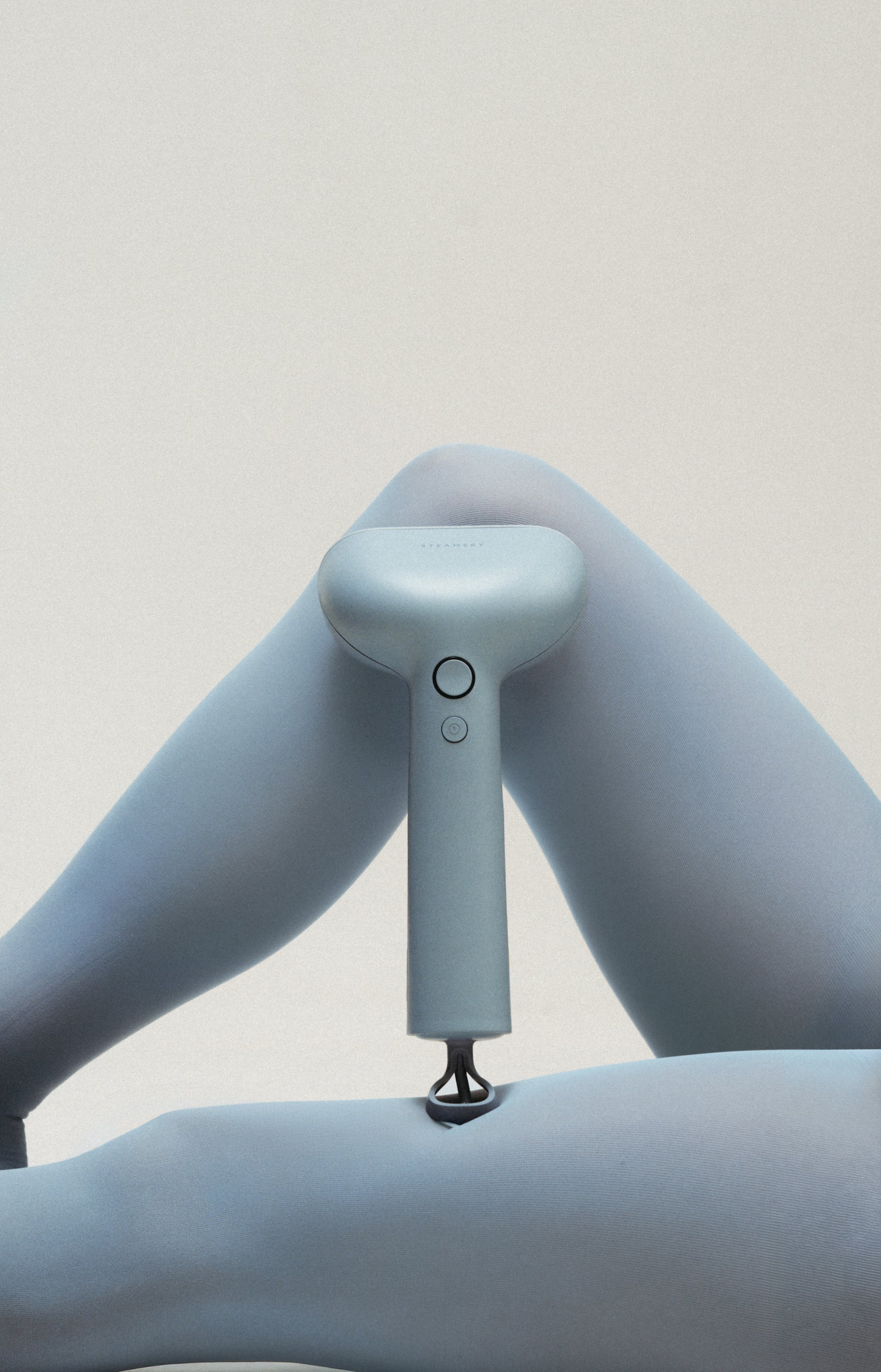 Light blue handheld steamer held by a person against a plain background