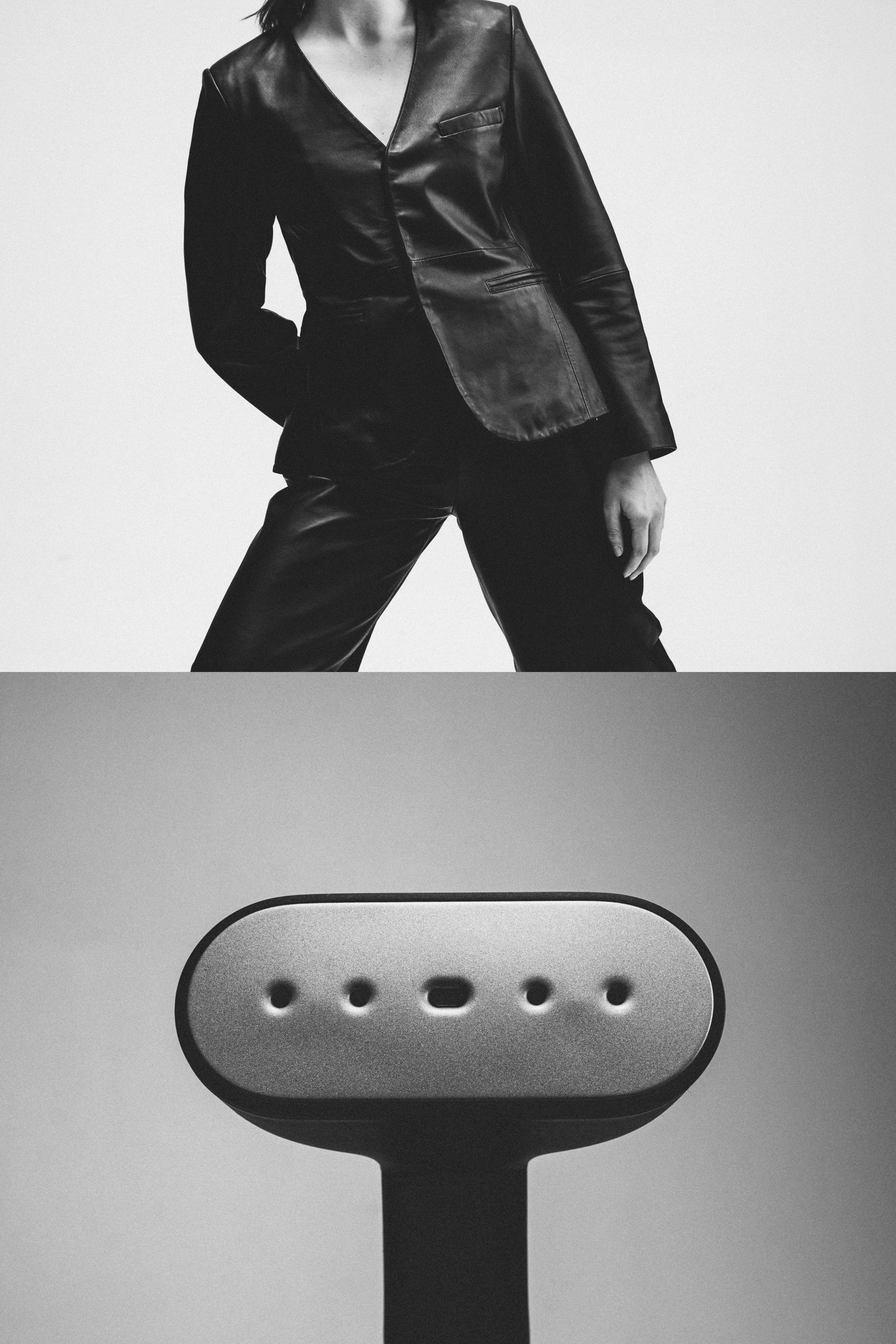 Person wearing a black leather jacket with a close-up of a black steamer below.