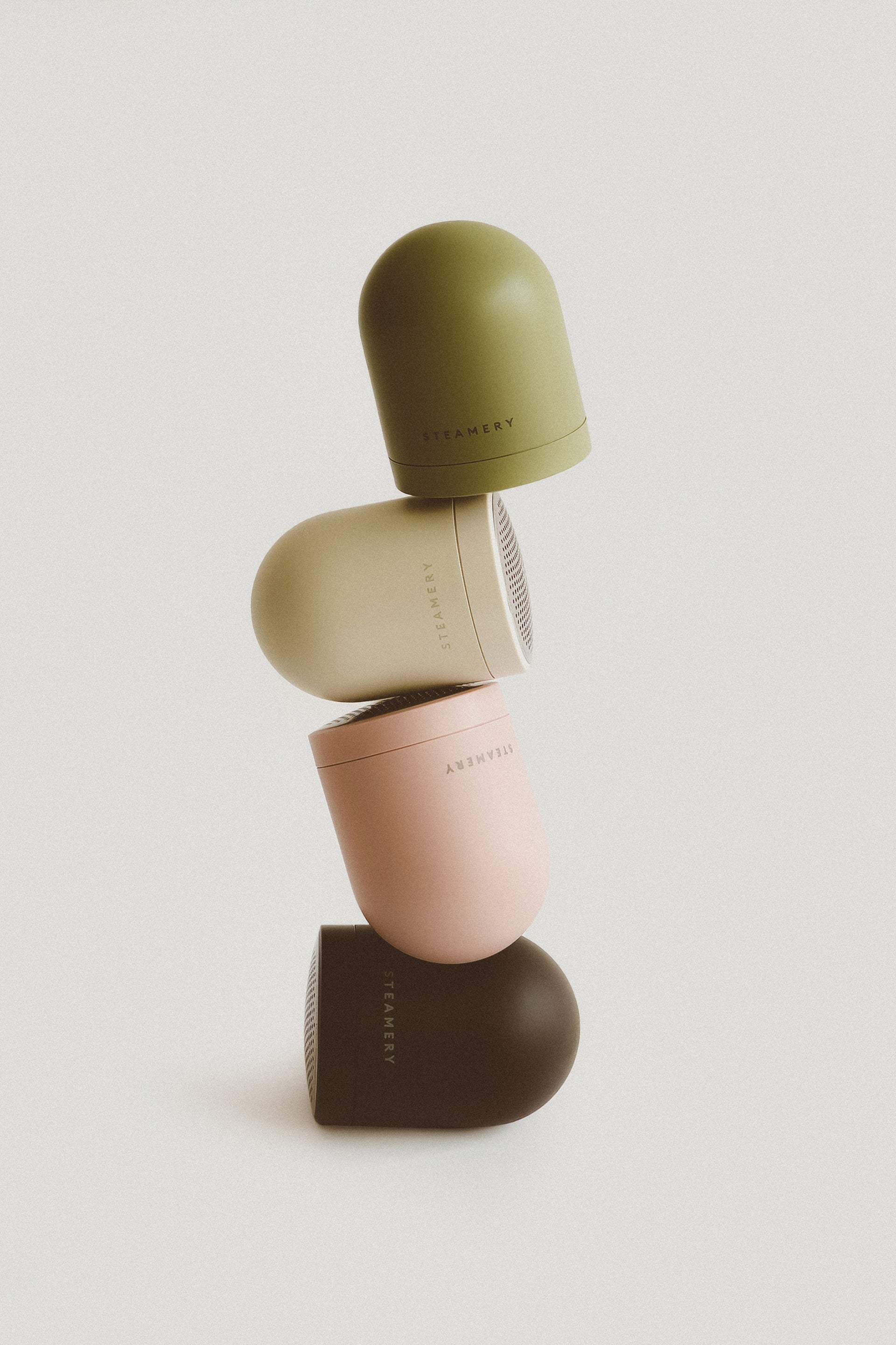 Stack of four green, beige, pink, and black fabric shavers on a beige background