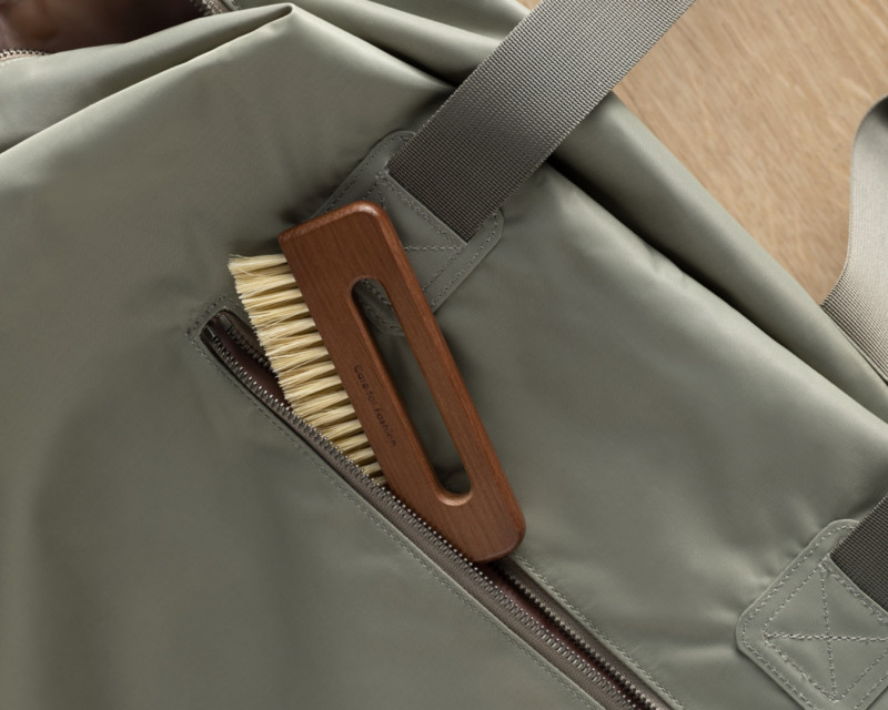 A Pocket Brush peeking out of a green duffel bag