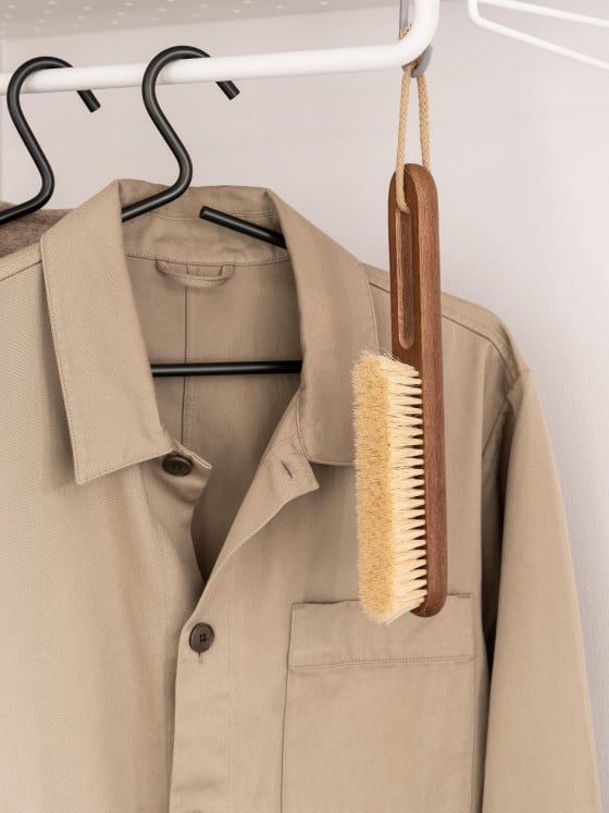 Steamery Clothing Brush hangs on a clothing rack.